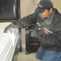 Bed bug inspection technician checking a mattress and bed frame for signs of infestation in Shreveport, LA